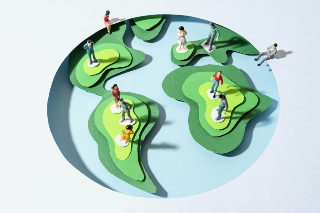 Miniature figures standing on a stylized globe, representing global adoption trends in renewable energy.