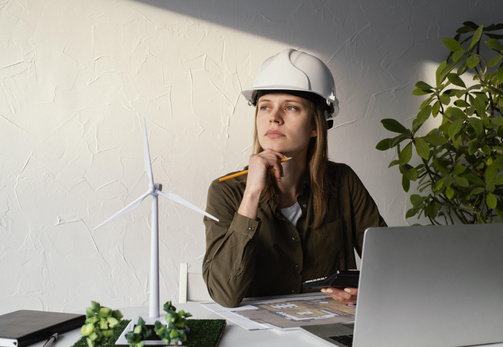 Engineer wearing a hard hat, contemplating a wind turbine model, representing renewable energy risk management